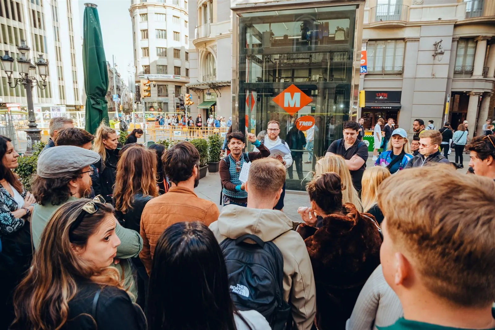 A guide briefing a large corporate group near a Barcelona metro entrance