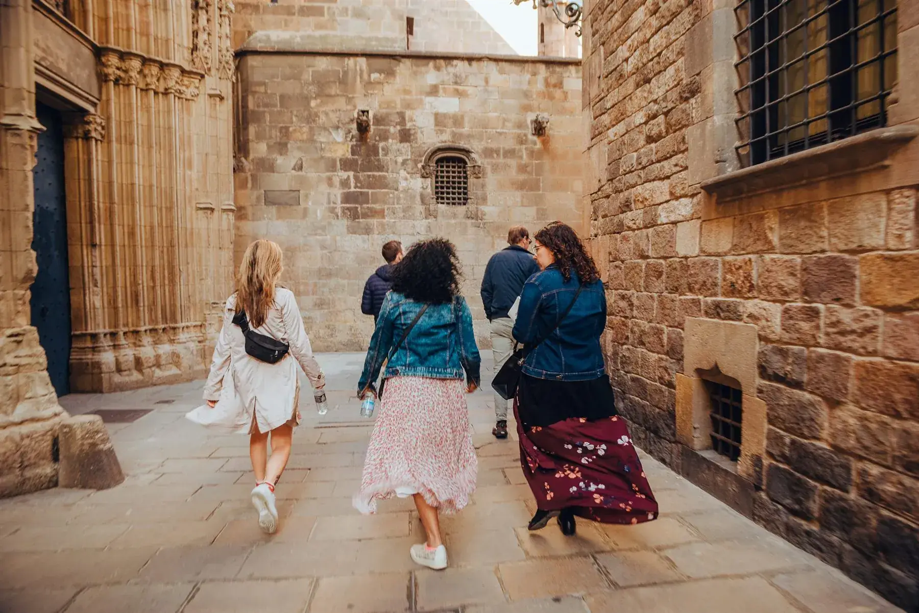 A team walking together through a golden-lit stone alley near Barcelona Cathedral