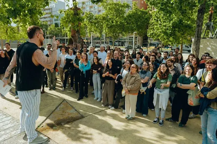 A guide briefing a large, smiling corporate group in a Barcelona plaza